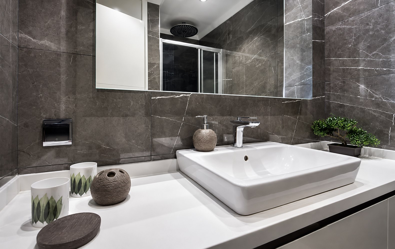 Vanitorio con superficie de mármol gris y lavabo blanco